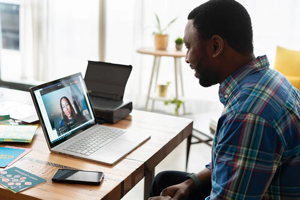 A man sitting at a table with a laptop and phone.