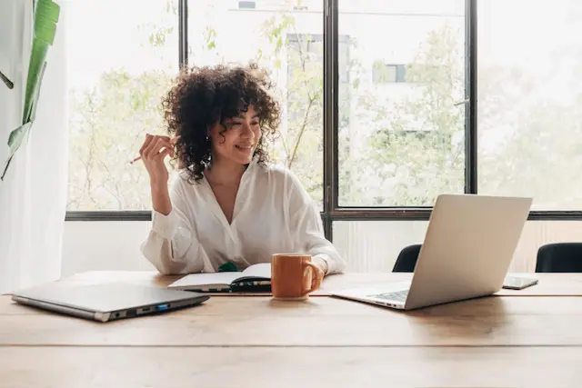 A woman sitting at a table with her laptop.