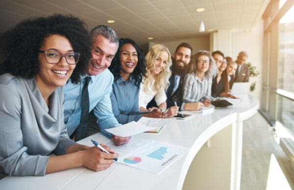 A group of people sitting at a counter with papers.